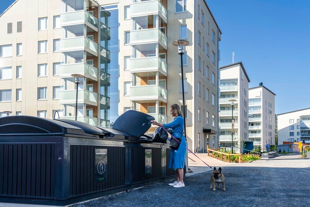 Nainen vie roskia MolokDomino syväkeräyssäiliöön